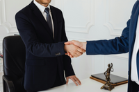 Dos abogados dándose la mano en una oficina, símbolo de acuerdo y confianza profesional